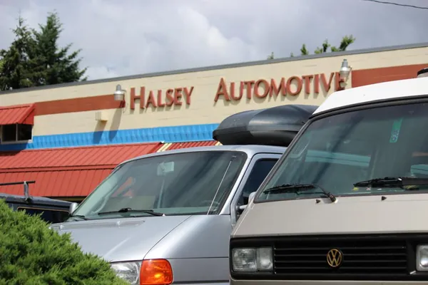 Vans, including a Volkswagen, parked in front of the Halsey Import Parts building