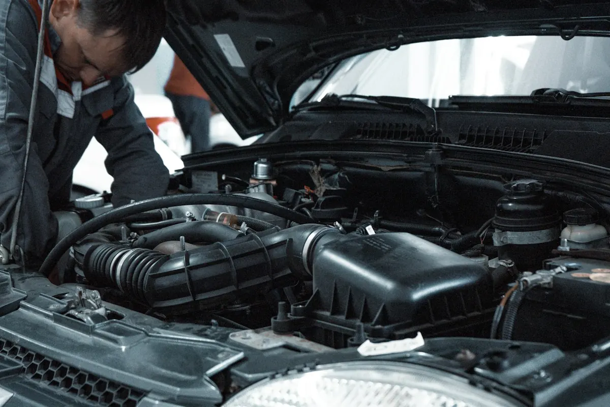 Mechanic in a grey work shirt leaning over an open engine bay
