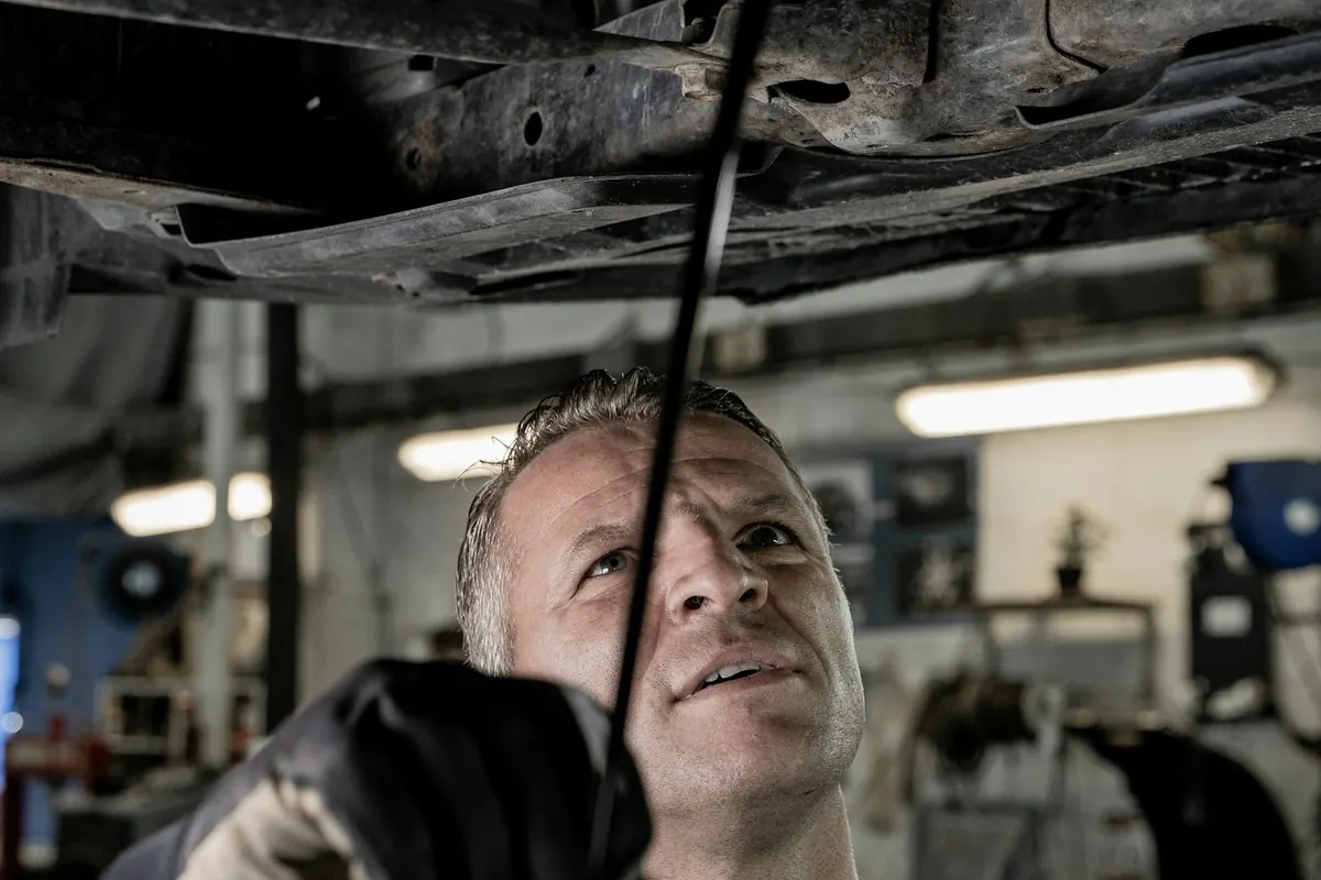 Mechanic looking up while working beneath a car on a shop lift
