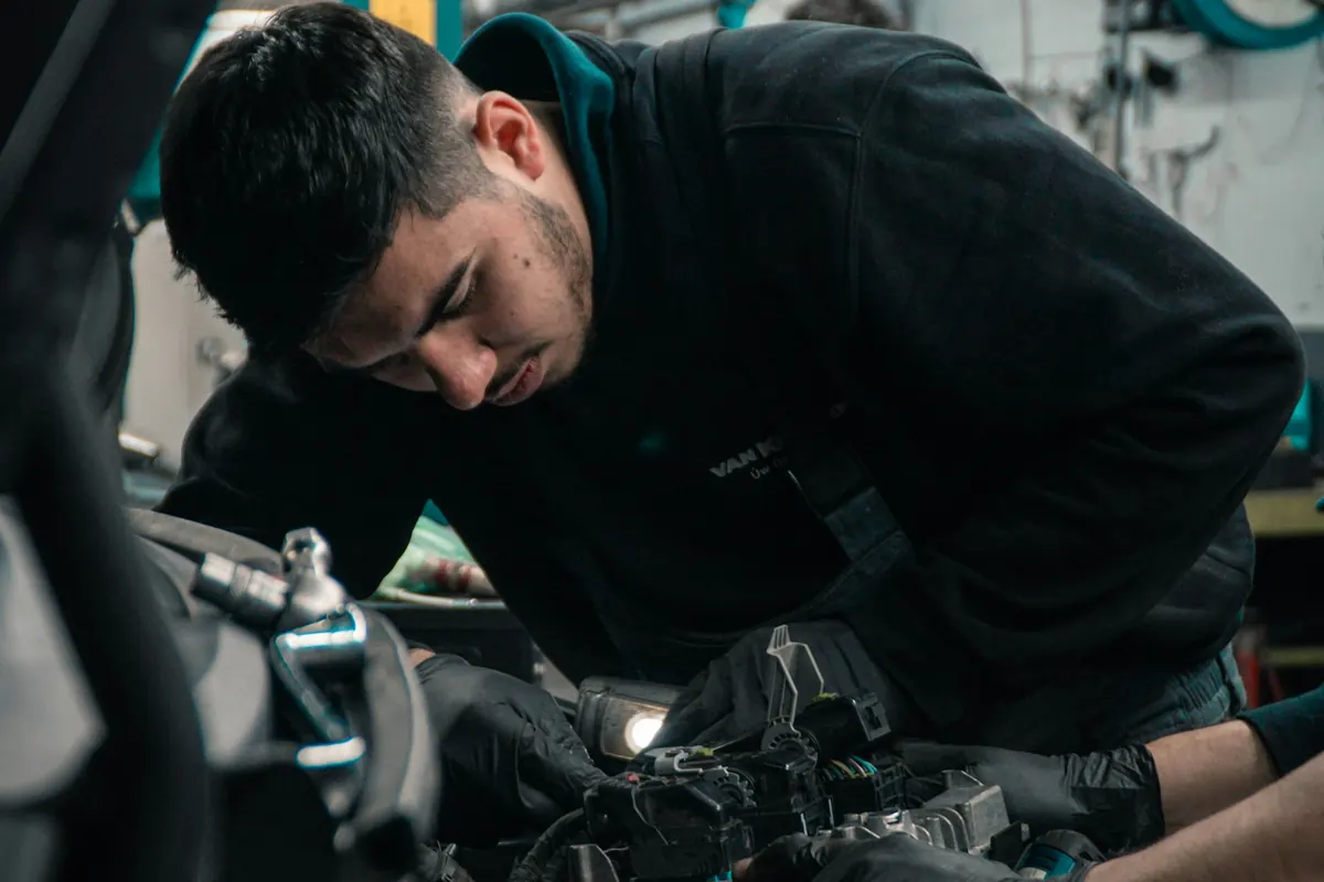 Mechanic in gloves working on an engine under an open hood
