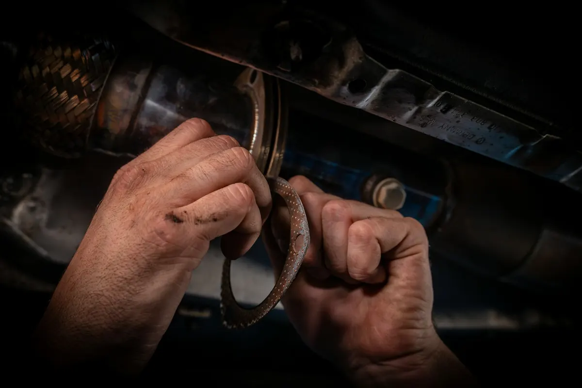 Hands with a wrench working on the underside of a car