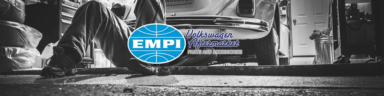EMPI Volkswagen Aftermarket Parts and Accessories banner, over a black-and-white photo of a mechanic lying under a classic Volkswagen